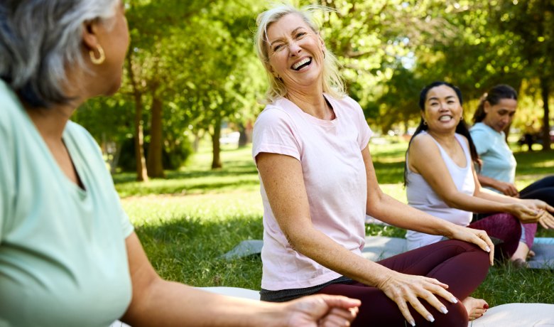 Women laughing together during an outdoor stretching class